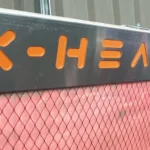 a closeup of an X-Heat Heater, it's on, the inside of it is glowing red and the logo is orange and reads 'X-HEAT'