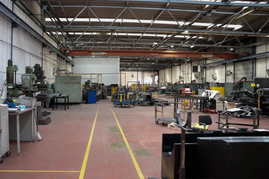 a warehouse with 9 x-heat heaters in view, most of them are one the right wall, which is white and made out of bricks.