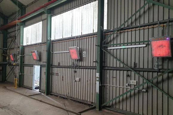 a grey walls with ridges on it that has 4 x-heat heaters on it, they are spread apart.